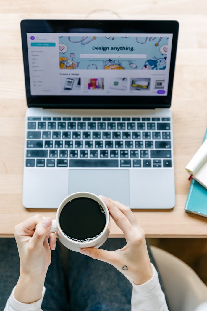 Crafting Captivating Headlines: Your awesome post title goes here A cozy workspace with hands holding coffee over a laptop, perfect for design inspiration.
